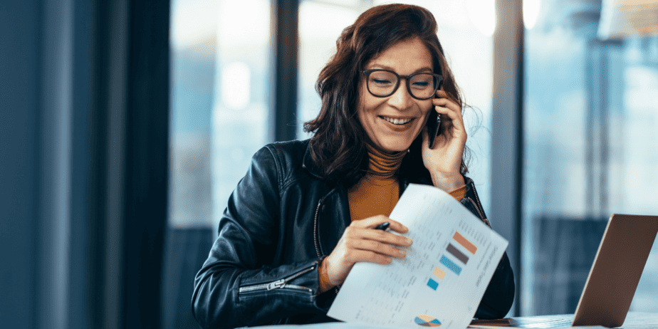 business woman happily on phone doing paperwork